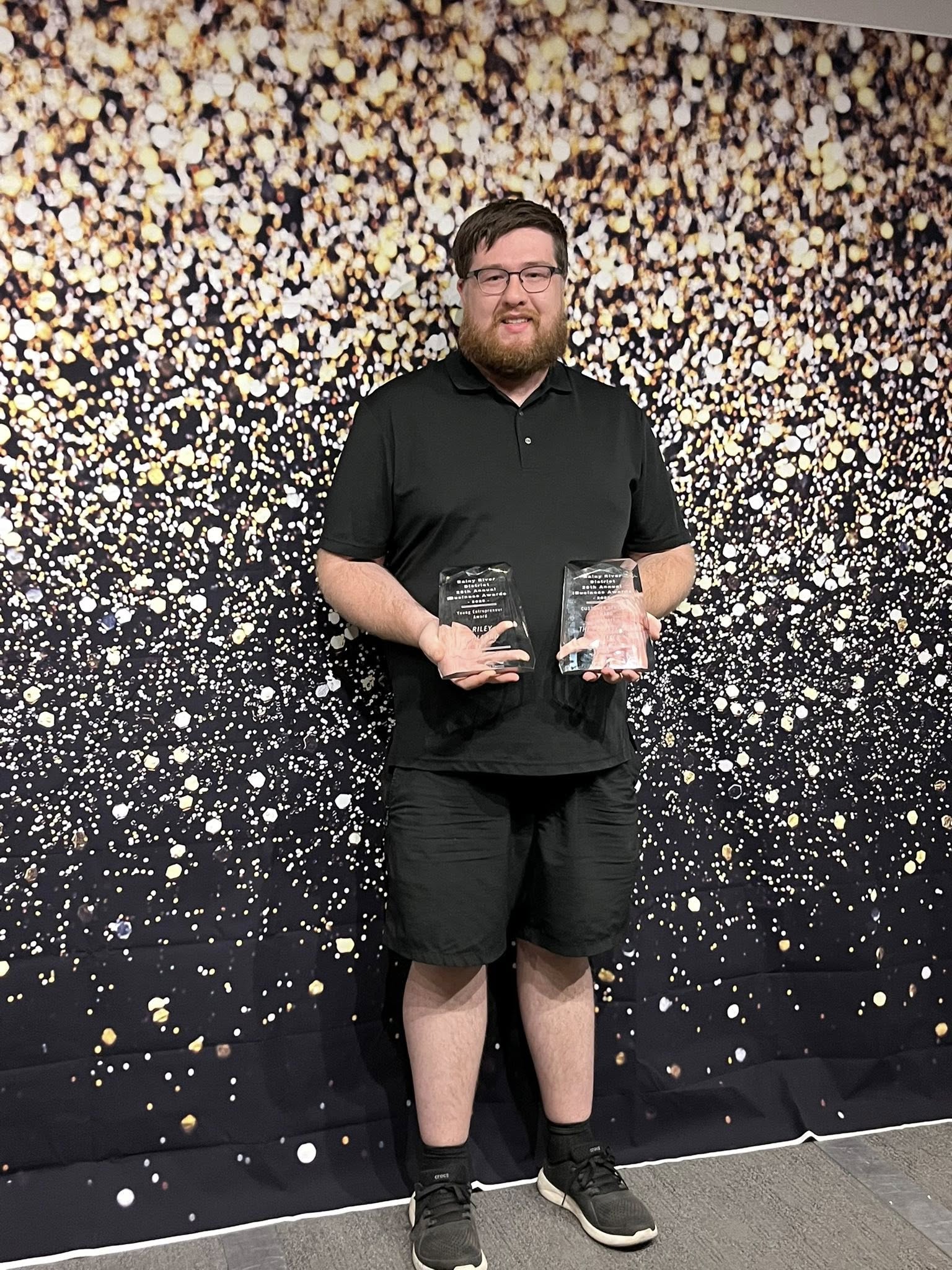 Riley Pollard holding two business awards
